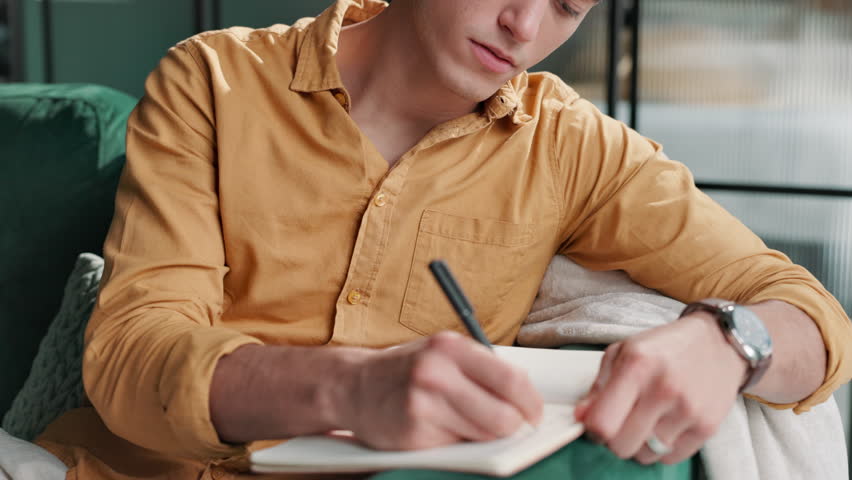 Home, man or writing in book on sofa with diary, journal and thinking of inspiration with happy memory. Writer, person or notebook on couch for schedule, planner or reminder for to do list with smile