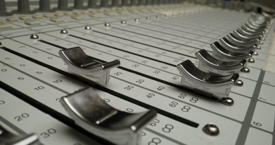 A man controls a mixing console while recording audio in the studio. Close-up of his hand, an unrecognizable person