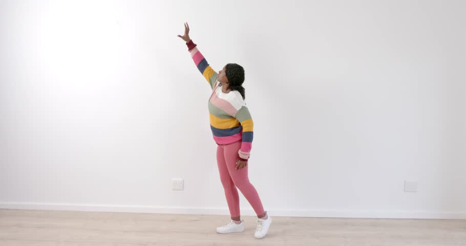 High speed photography for dynamic scenes, Reaching up, woman in colorful sweater and pink leggings posing indoors. Fashion, vibrant, trendy, modern, style