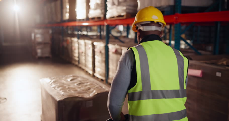 Man, pallet and walking with stock in warehouse for loading or shipping, inventory management and transport of goods. Male person, boxes and supply chain in logistics factory for packaging and order