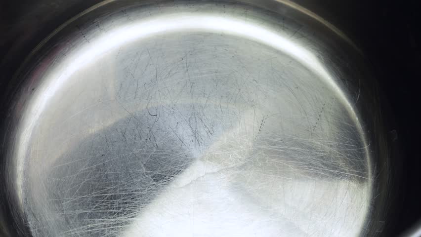 Water is poured into the bottom of a metal pan. Slow motion.