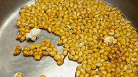 Popcorn grains are fried in vegetable oil and popping at the bottom of a metal pan. Slow motion. - Powered by Shutterstock - Get 15% off with code: PIKWIZARD15