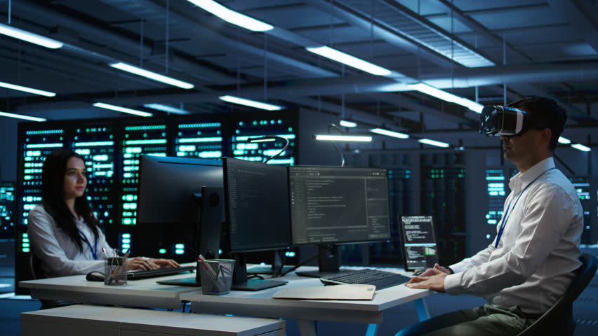 Data center admin responsible for installation of networking systems wearing high tech VR headset. IT worker doing maintenance on server farm gear using virtual reality technology, camera B - Powered by Shutterstock - Get 15% off with code: PIKWIZARD15