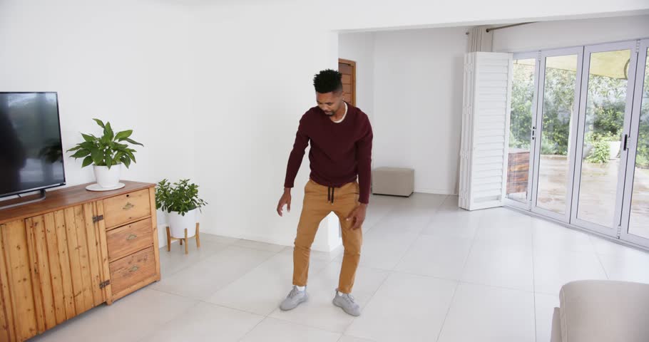 High speed photography for dynamic scenes, at home, man in living room with plants and tv. people, movement, full body, picking up