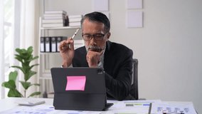 Mature businessman focused on tablet, analyzing charts and data in office with shelves, plants, and natural light - Powered by Shutterstock - Get 15% off with code: PIKWIZARD15