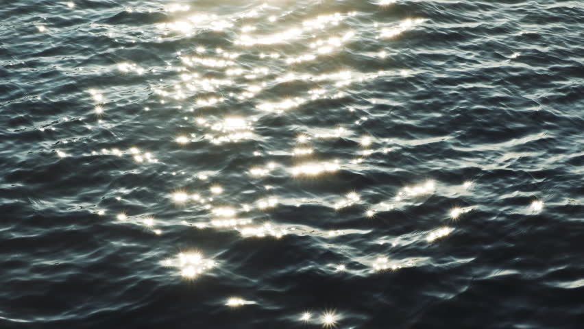 Slow motion of golden glittering sea surface, abstract background.