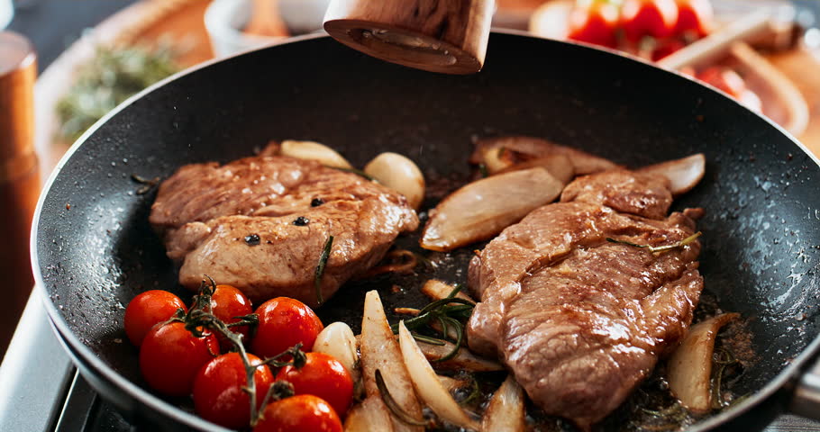 Cooking, meat and frying pan in restaurant, spices and sprinkles for taste of food and meal prep in hotel. Cuisine, hospitality and beef for fine dining with culinary skills, luxury and hands of chef