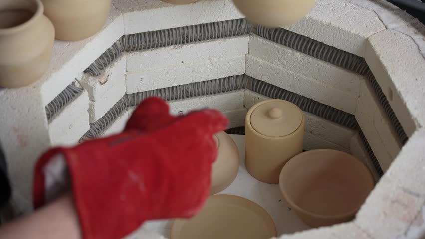 Close-up of male hands taking ceramics into a special kiln. 