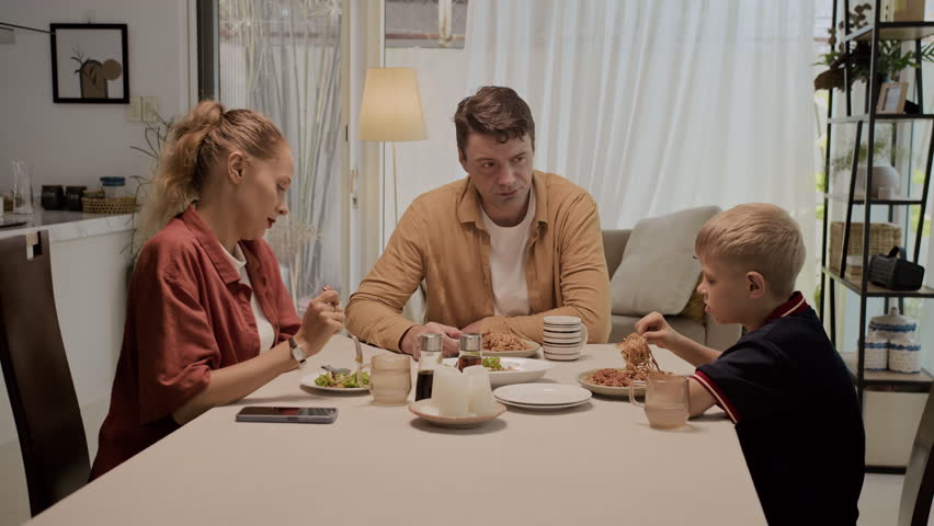 Wide shot of Caucasian family having serious talk while dining together at home table