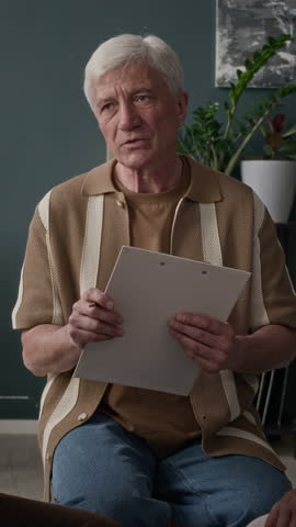 Vertical medium shot of Caucasian senior man giving lecture on mental health maintenance to group of people in circle