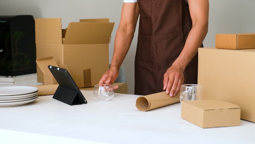 Securely wrap and pack fragile glass item in paper for safe shipping or storage. Efficient packaging for transport