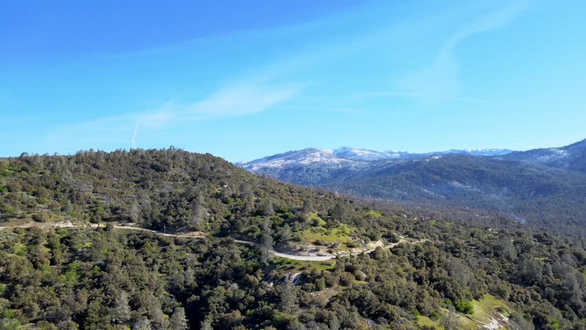Aerial view of Yosemite National Park, green forests, rolling hills, snow-capped mountains, clear blue sky, scenic landscape, nature