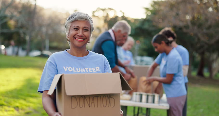 Portrait, mature woman and volunteer with box in nature, donation and contribution for community service. NGO, smile and female member in park with pride, charity or package for social responsibility