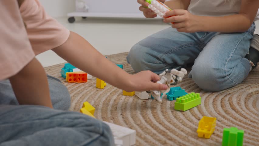 Young teacher and group of children sitting on the floor and playing toy constructor in developmental classes. Children education concept. Slow motion.