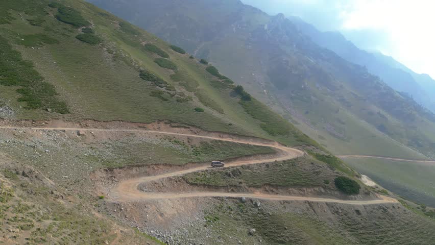 Aerial view of mountain serpentine road with moving car. Road in the mountains leading to Badgoi Top, Swat Valley, Pakistan.