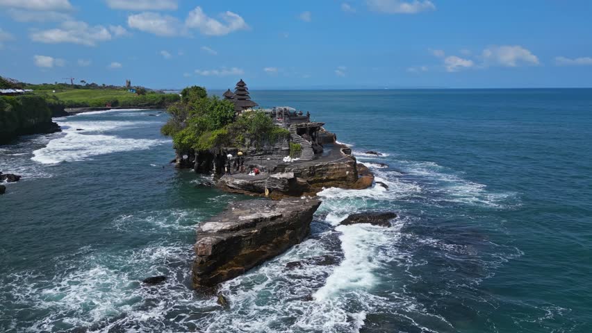  Waves crash and dance around its rugged base, Tanah Lot, aerial parallax