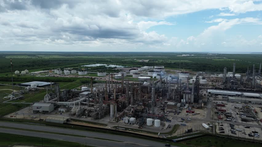 Flyover highway near large oil refinery complex plant with gas flare, crude oil distillation unit, storage tanks, utility systems, pipelines in rural agriculture agro-town San Antonio, Texas. USA