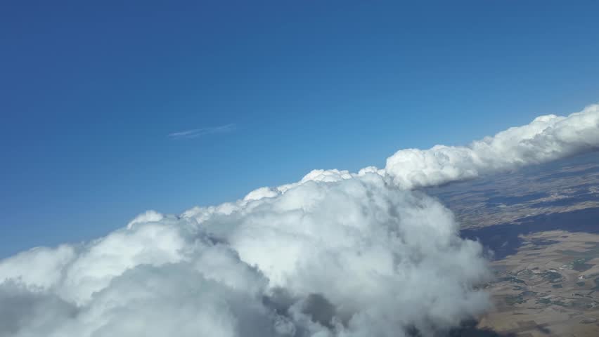 Immersive pilot POV flying through some fluffy white clouds in a splendid blue sky. 4K 60FPS