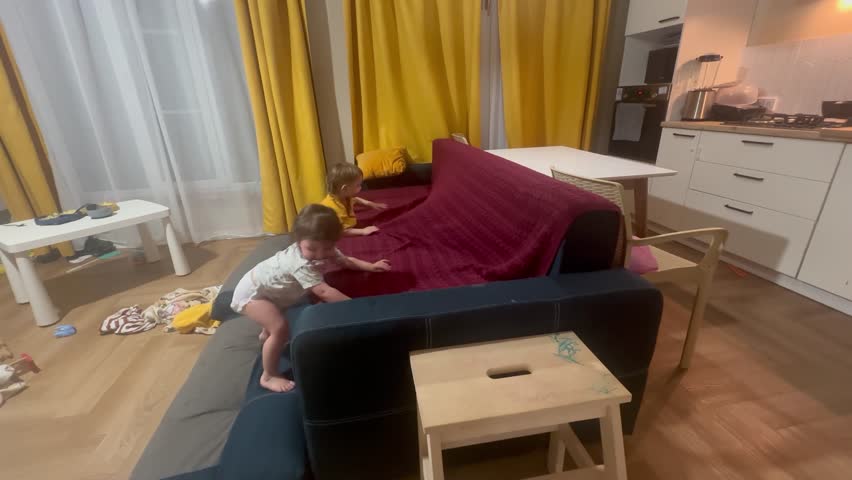 children playing on the sofa. happy family kid dream concept. children play getting on and off the sofa. little boy and girl playing on a blue sofa at lifestyle home, close up