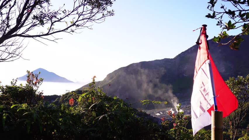 Indonesian flag flying on top of mountain with beautiful mountain views and clear sky. The Indonesian flag flies on Mount Papandayan, West Java, Indonesia