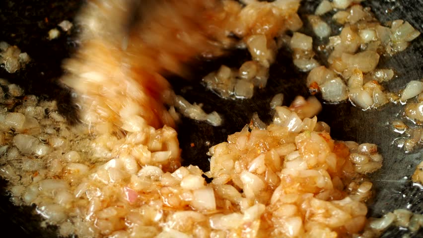 Frying chopped red onion in pan, in door Chiangmai Thailand.