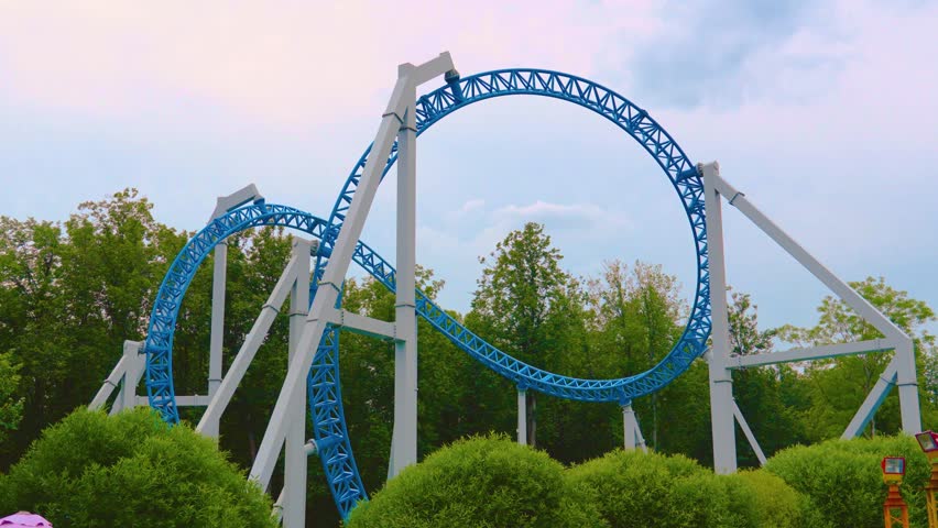 Loop metal frame of a roller coaster in an amusement park. Roller coaster cart with people riding it goes through a loop upside down