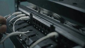 Male network administrator inserts cables into the server rack working with internet equipment in server room. Maintenance of LAN, computer networks and web servers. Data storage center. Close Up. - Powered by Shutterstock - Get 15% off with code: PIKWIZARD15