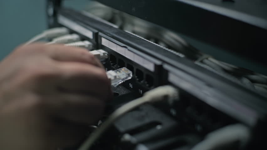 Male network administrator inserts cables into the server rack working with internet equipment in server room. Maintenance of LAN, computer networks and web servers. Data storage center. Close Up. - Powered by Shutterstock - Get 15% off with code: PIKWIZARD15