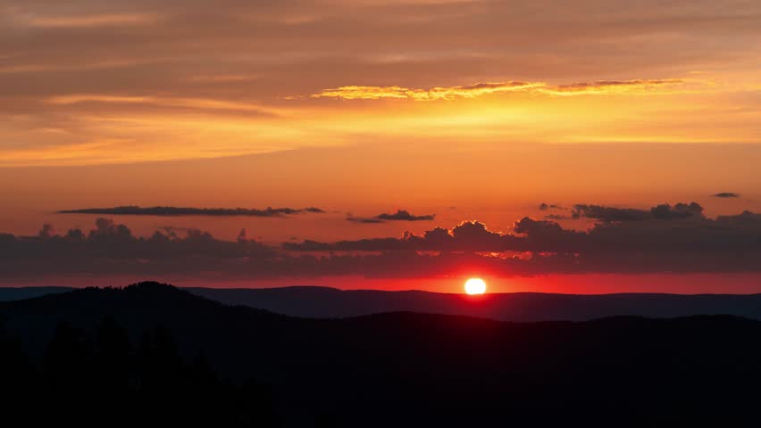 Vibrant orange sunset over mountains. Static shot time lapse