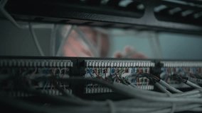 Male network administrator inserts cables into the server rack working with internet equipment in server room. Maintenance of LAN, computer networks and web servers. Data storage center. Close Up. - Powered by Shutterstock - Get 15% off with code: PIKWIZARD15