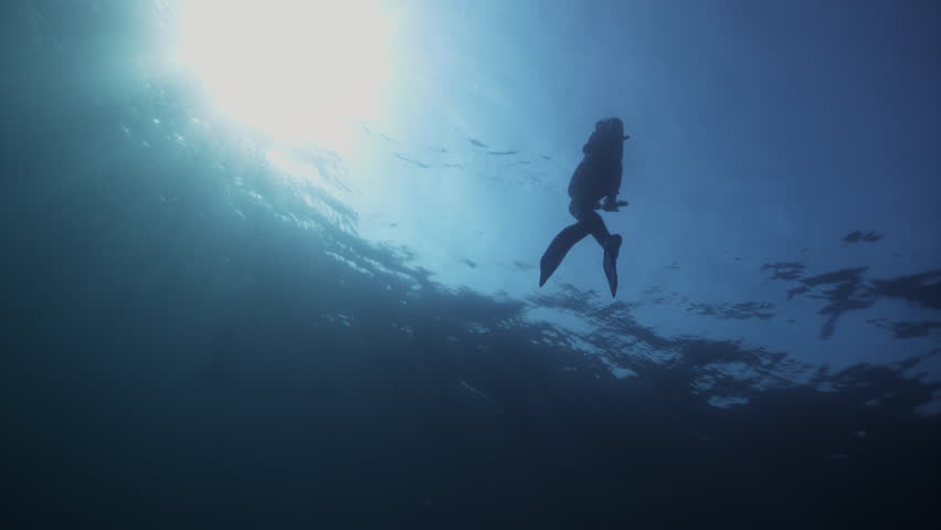 Young woman in full body costume snorkeling and swimming in sea Maldives. Free diver girl man swim dive in deep blue water. Active Sport, healthy lifestyle concept. Tranquility, calmness, peace vibe.
