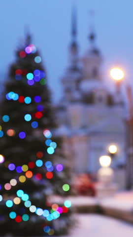 New Year Boke Lights Xmas Christmas Tree Decoration And Orthodox Church In Background. Festive Illumination, Natural Defocused Blue Bokeh Background Effect. Zoom Out