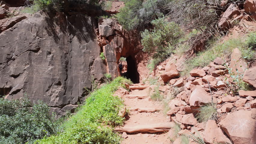 Rock tunnel on hiking trail, pan to gorge. Grand Canyon, USA.