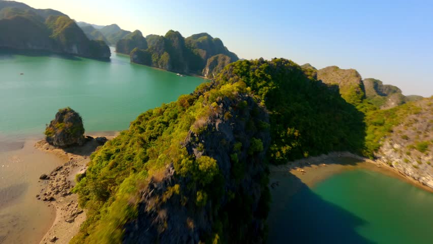 Cinematic FPV flight close to scenic limestone rocky islands on Ha Long Bay in Vietnam