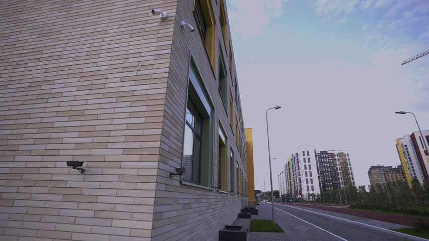 Well-maintained sidewalk runs parallel to row of residential buildings. Pavement for pedestrians to explore residential neighbourhood