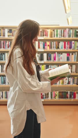 Unrecognizable brunette browsing a book in a library or bookstore, exam preparation, teacher training, higher education, e-learning for students, research project work for masters, bachelors, interns