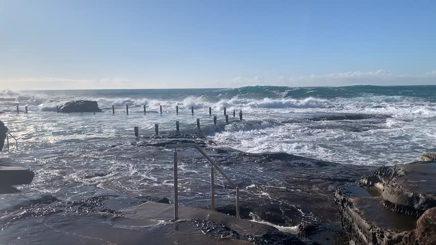 Large waves splash over the shoreline along the rock pool at Maroubra Beach Sydney Australia, windy and big waves tide
