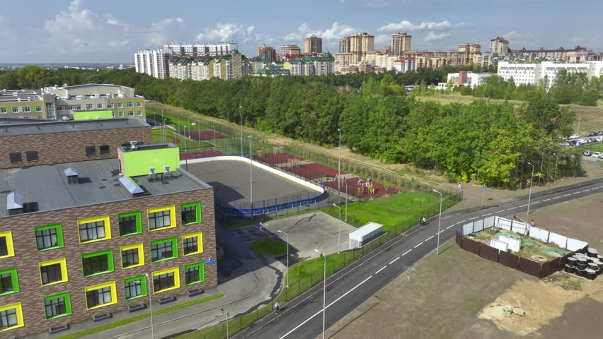 Modern building of school stands next to large sports arena. Contemporary sports arena includes facilities for wide range of sports