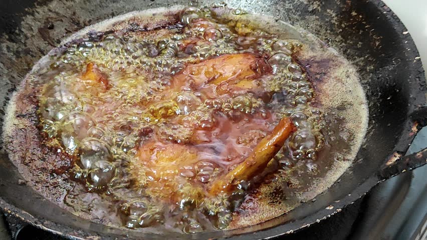 4K footage of Frying chicken in a old wok or pan on a stove