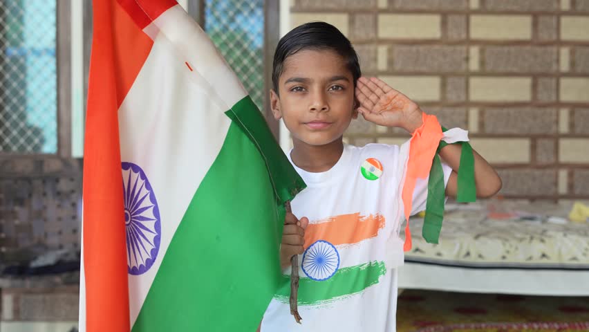 Indian village kids wearing national flag logo design printed t shirt and holding, waving or running with Tricolour with greenery in the background, celebrating Independence or Republic day