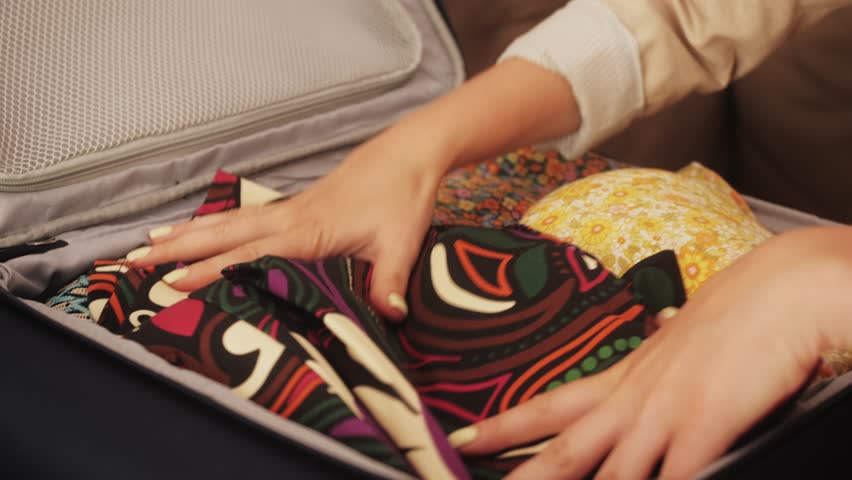 Woman getting ready for travel and packing clothes. Tourist is collecting a suitcase for leisure. Preparing for a trip. Concept of traveling and vacation