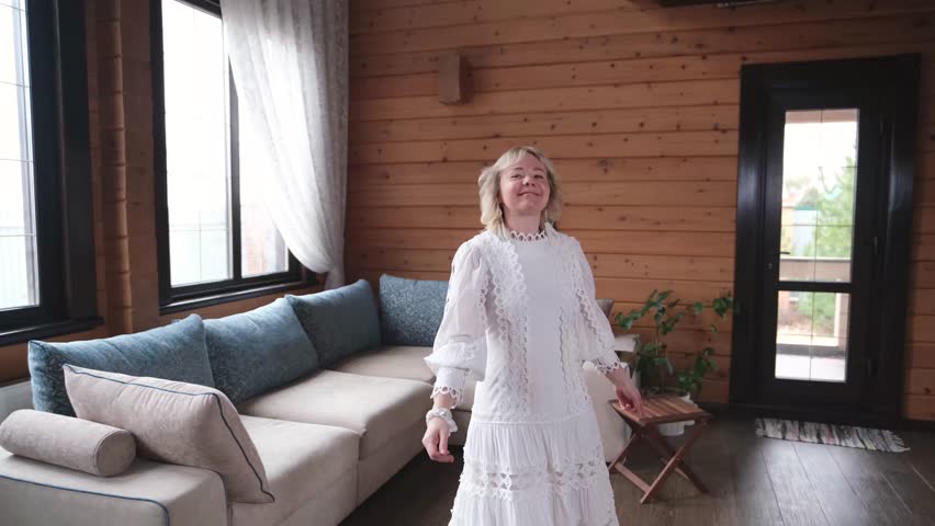 Happy young woman in traditional white dress spinning in big wooden house