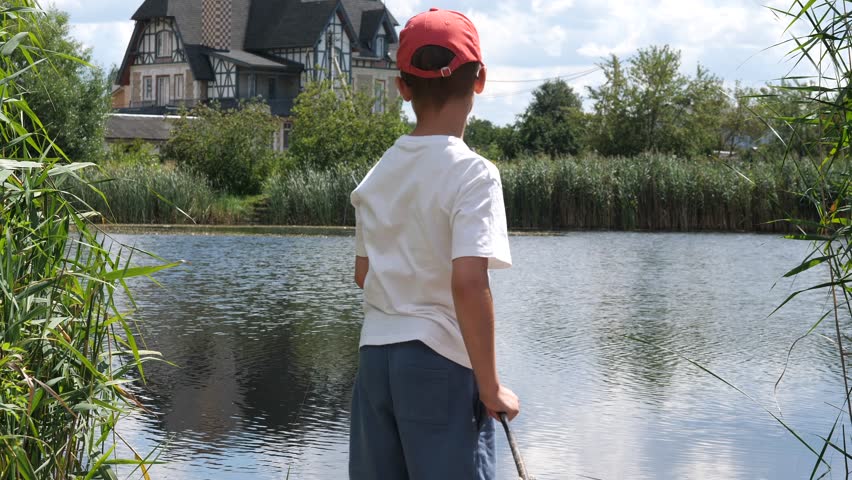 boy fishing on the lake shore. Boy with wooden fishing rod trying to catch fish