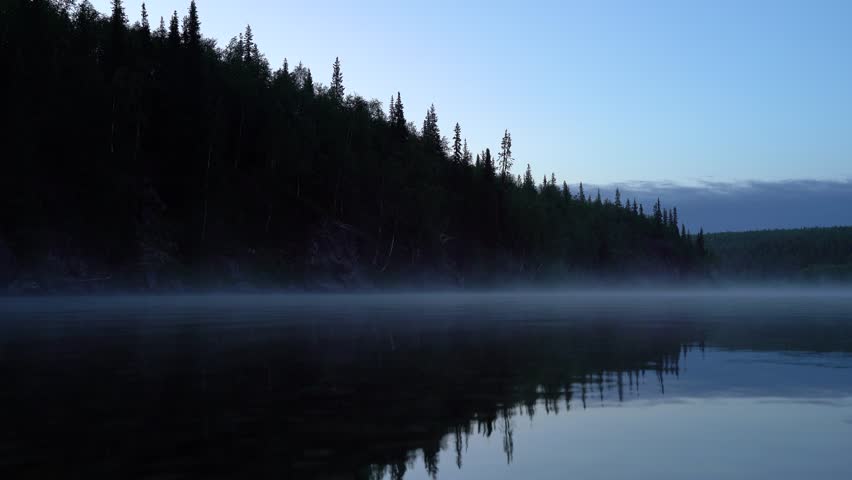 Calm river against the background of a black cliff with forest at night