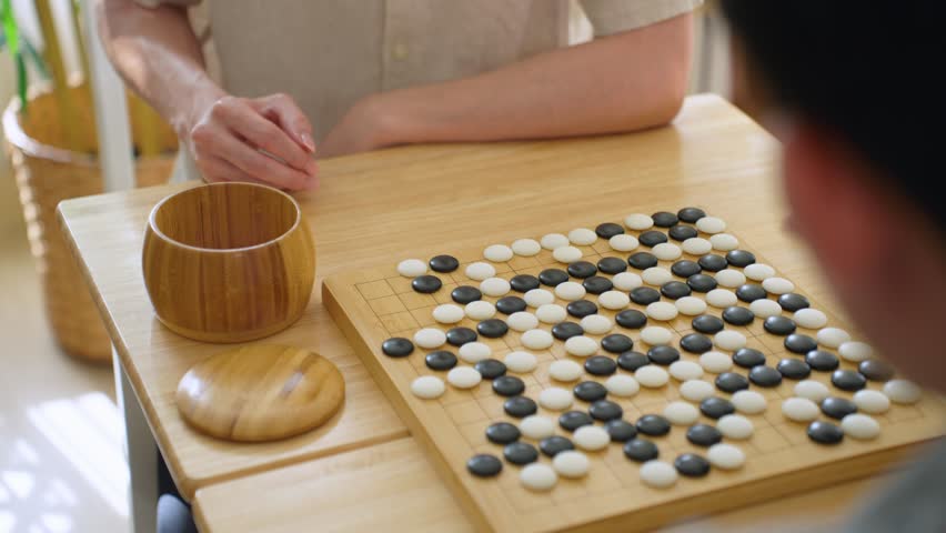 Close up of young men play board game Go during competition in community. Attractive two male friend players participate in traditional asian chinese board game match on table in the club house center