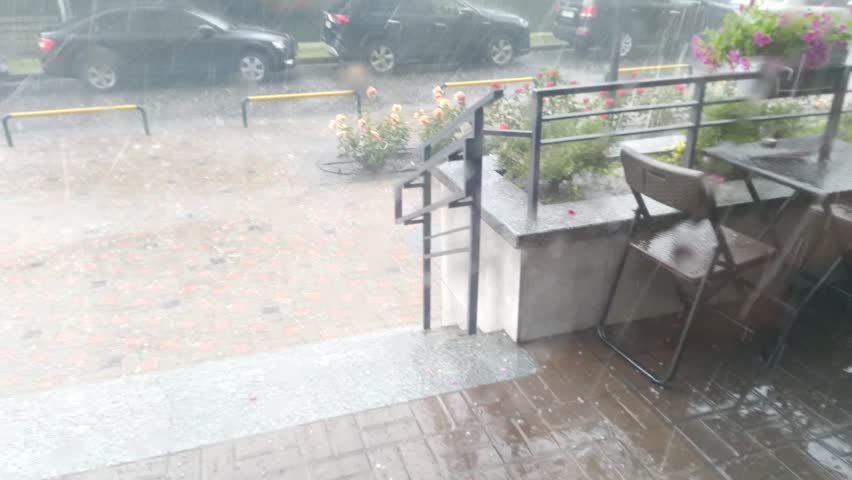Rain, thunderstorm and hail on the porch of the house. Strong storm hurricane. Bad weather in the city. Storm