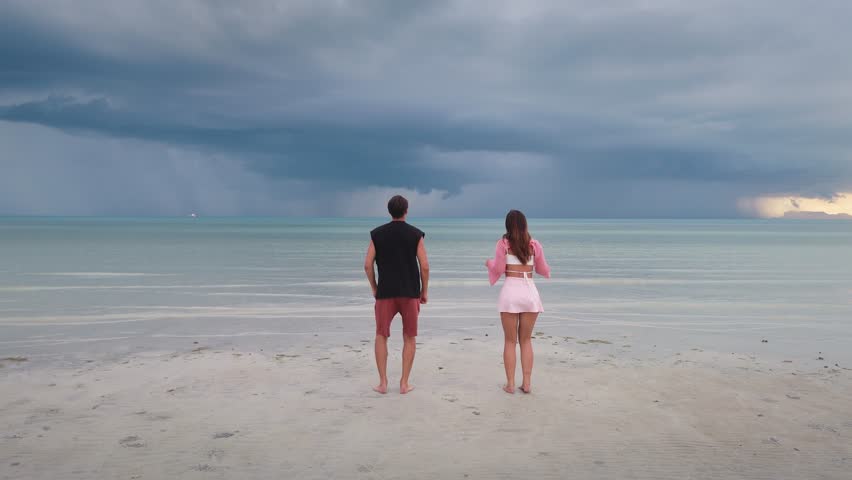 Loving couple by sea jumping playfully then sharing gentle embrace joy companionship love amidst ocean