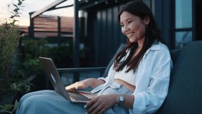 Portrait of beautiful young asian woman having video call conference meeting interview by laptop computer at home balcony Smiling female talking on working or personal conversation on sunset - Powered by Shutterstock - Get 15% off with code: PIKWIZARD15
