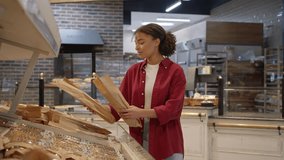 Attentive woman in red shirt picking french baguette at craft bag and smiling to preteen son coming with treats in hands. Cute kid running to mother and asking to buy sweets in plastic containers. - Powered by Shutterstock - Get 15% off with code: PIKWIZARD15