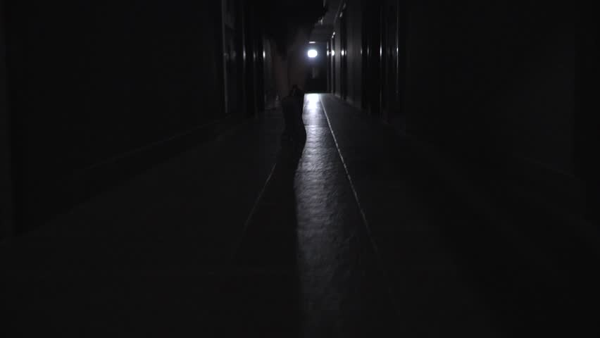 a girl in coarse boots with untied laces runs along a dark corridor. back view